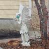 A masked fairy statue stands in a front yard